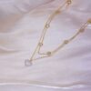 a gold chain necklace with a heart pendant on a white fabric