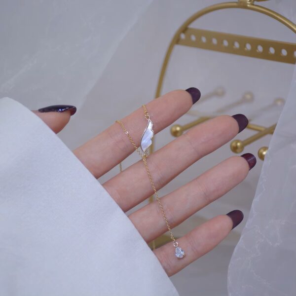 a hand with a gold Necklace diamond ring