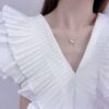 a woman necklace wearing a white ruffle shirt