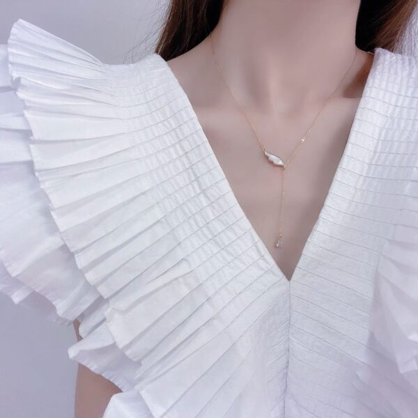 a woman necklace wearing a white ruffle shirt